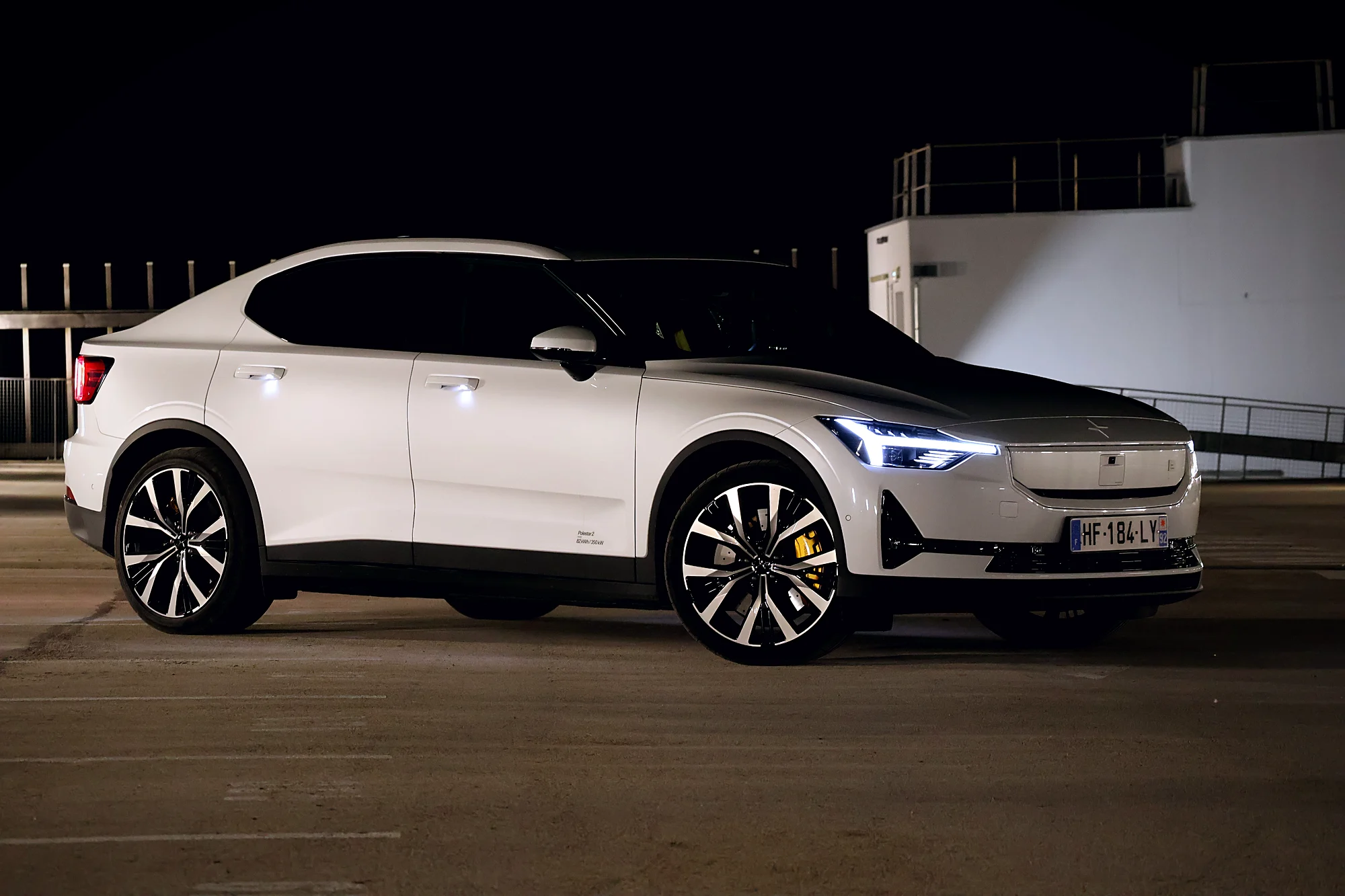 Polestar 2 de nuit, trois quarts avant, feux allumés