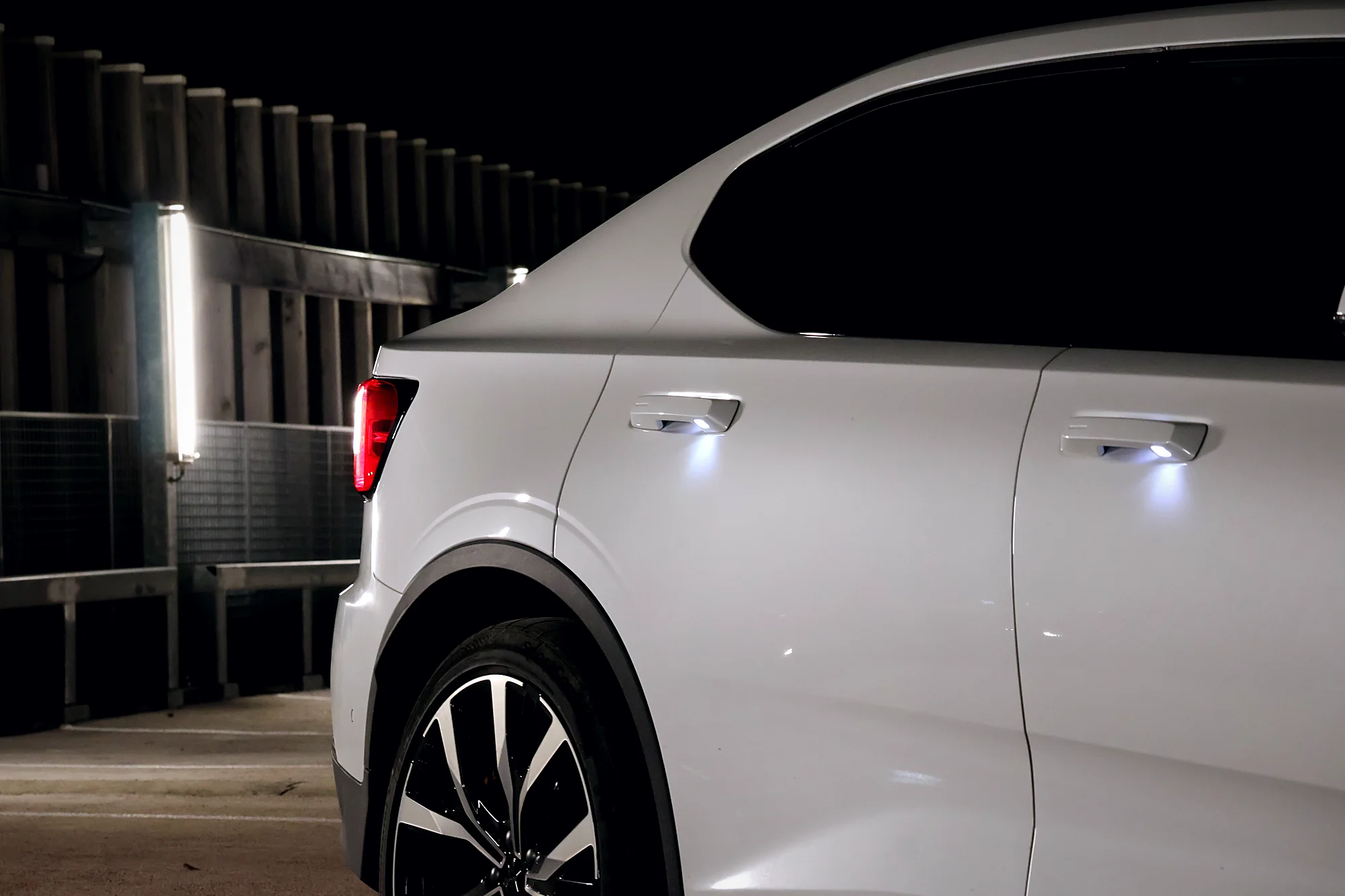 Flanc arrière de la Polestar 2 de nuit avec les poignées éclairées
